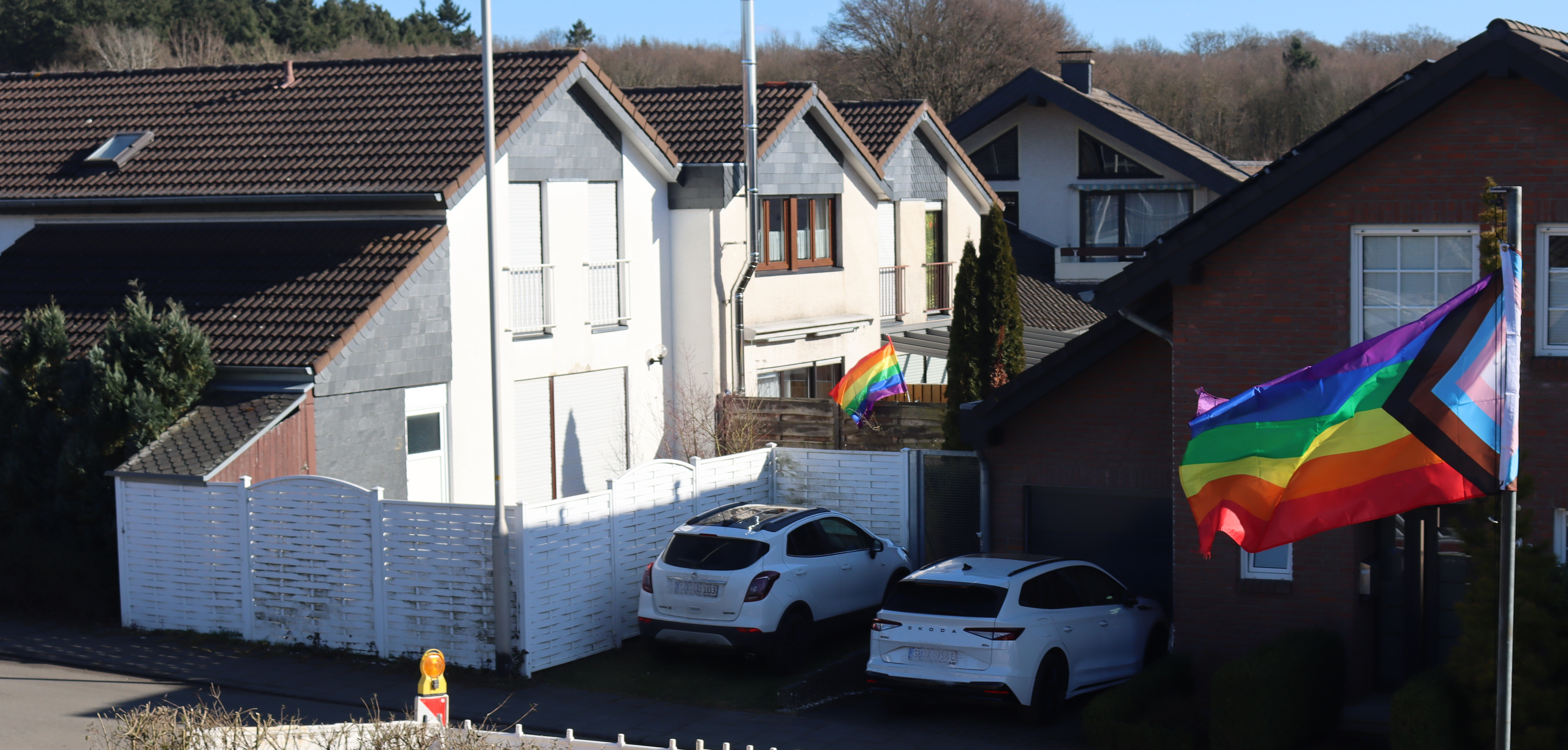 Zwei Regenbogenfahnen in einem Wohngebiet