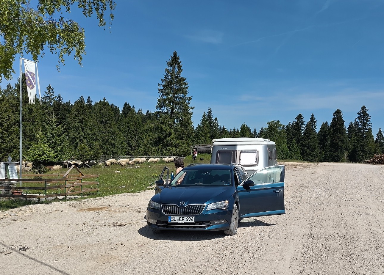 Ein staubiger Skoda mit Wohnwagen auf einer Schotterpiste